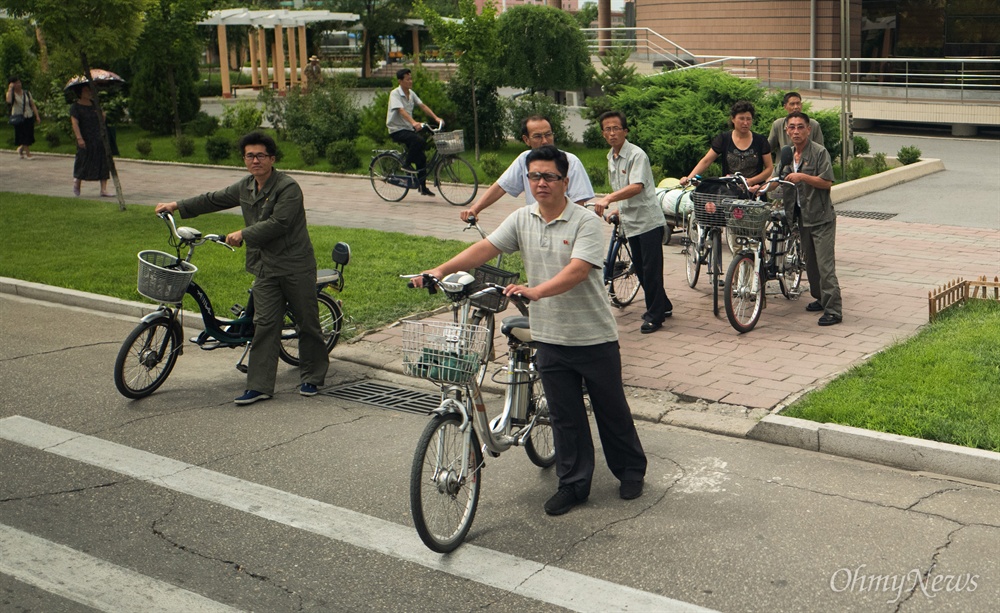  6일 오전 평양 시내에서 전기자전거를 탄 주민들이 길을 건너기 위해 서 있다. 
