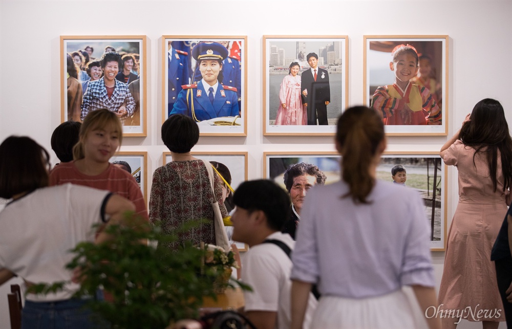  1998년 부터 2003년 까지 촬영한 북한 사진으로 열린 <사는거이 다 똑같디요> 전시를 관람객들이 자세히 들여다 보고 있다.