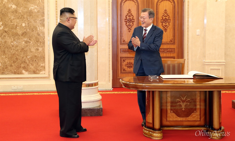  문재인 대통령이 18일 오후 평양 노동당 본부청사에서 방명록에 서명한 뒤 김정은 국무위원장의 박수에 화답하고 있다.