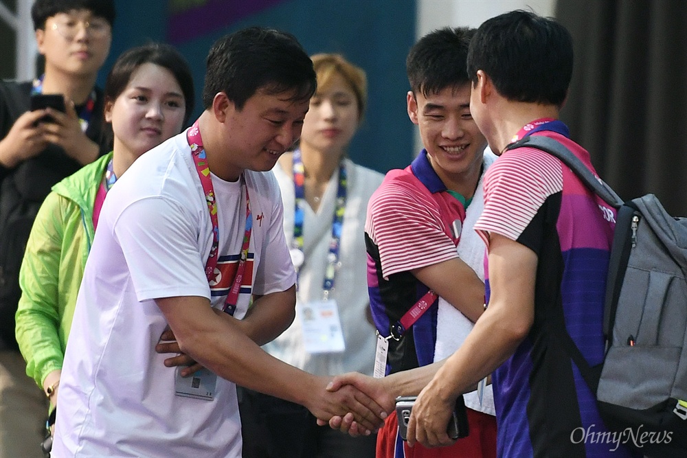  '2018 인도네시아 장애인아시아경기대회' 탁구 남북 단일팀 남측 문창주(오른쪽) 감독과 북측 리철웅(왼쪽) 감독이 5일 오후(현지시간) 인도네시아 자카르타 이컨벤션에서 만나 인사를 나누고 있다. 가운데는 북측 김영록 선수.