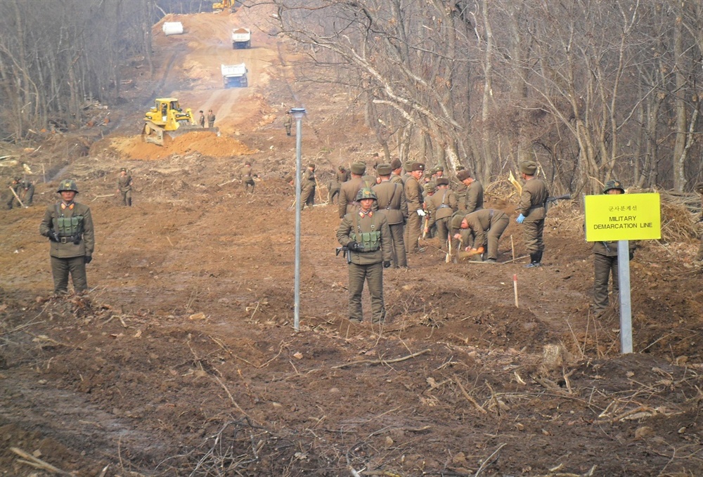 남북 공동 유해발굴 도로개설 남북이 22일 오후 공동유해발굴을 위한 지뢰 제거 작업이 진행 중인 강원도 철원 비무장지대(DMZ) 내 화살머리고지에서 전술 도로를 연결한다고 국방부가 밝혔다. 사진은 최근 도로연결 작업에 참여한 남북인원들이 군사분계선(MDL) 인근에서 작업하는 모습. [국방부 제공]