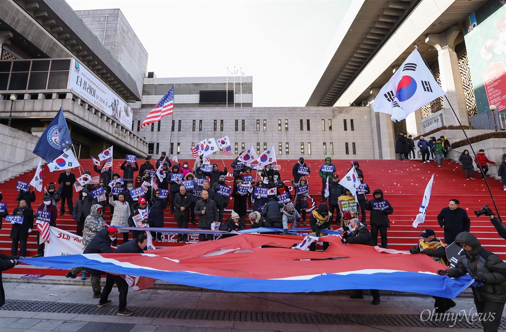  태극기혁명국민운동본부 회원들이 7일 오후 서울 종로구 세종문화예술회관 계단에서 열린 김정은 방남 반대 기자회견 도중 인공기를 찢는 퍼포먼스를 하고 있다.