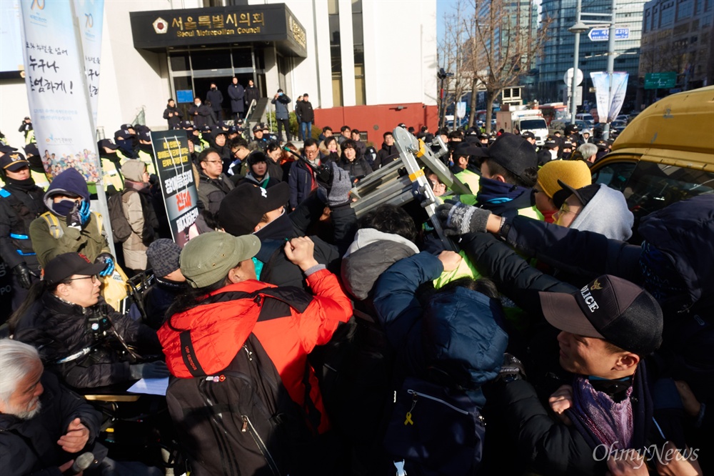  전국장애인차별철폐연대 소속 회원들이 10일 오전 세계인권선언 70주년 기념식이 열리는 서울 중구 대한성공회 서울주교좌성당 앞에서 ‘장애등급제폐지 예산반영을 위한 농성 투쟁보고 및 세계인권선언 70주년 기념 기자회견’을 열었다. 회견 도중 목에 거는 퍼포먼스를 위해 사다리를 펼치려하자 경찰이 저지하고 있다.