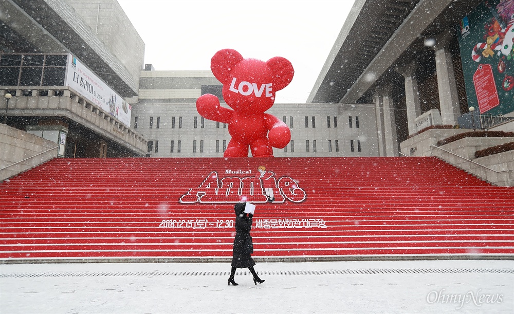 폭설에 묻히는 곰돌이 13일 오전 서울 도심에 폭설이 내리는 가운데, 세종문화회관 계단에 설치된 ‘HUG 베어’(임지빈 조각가)앞으로 한 시민이 지나고 있다.