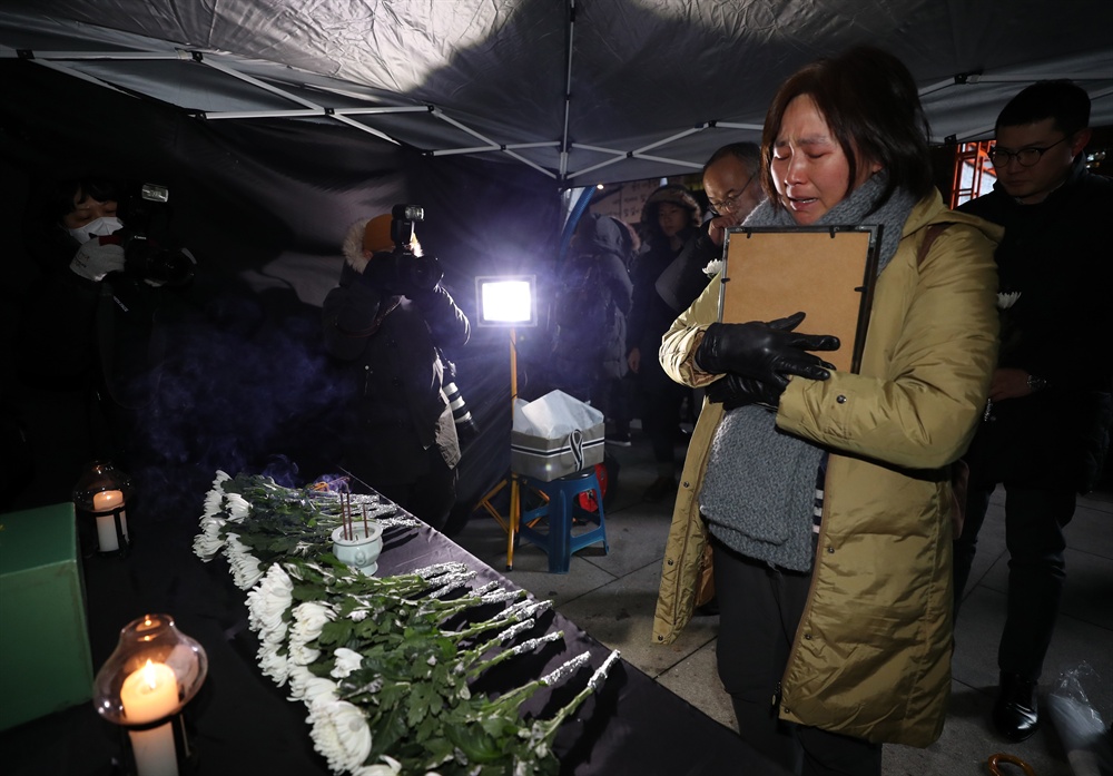  지난 13일 태안화력발전소에서 비정규직으로 일하다 숨진 김용균 씨의 분향소가 마련된 서울 광화문광장에서 한 추모객이 영정을 쓰다듬으며 눈물을 흘리고 있다.