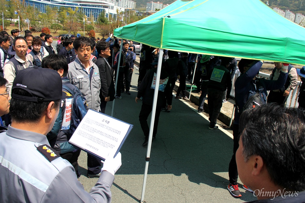  전국금속노동조합 경남지부 한국지엠창원비정규직지회가 4월 12일 중식시간에 한국지엠 창원공장 정문 앞에 천막농성장을 설치하가 한국지엠 관계자가 나와 고지문을 읽고 있다.