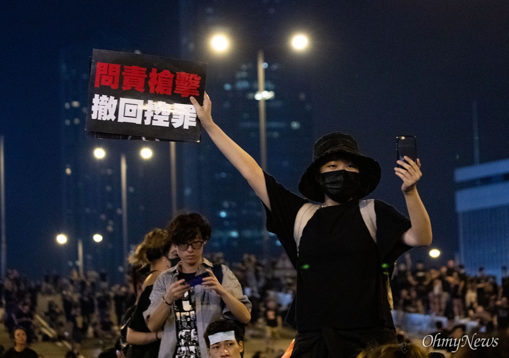  17일 오전 범죄인 인도법(일명 송환법) 폐지를 촉구하는 ‘검은 행진’에 참가한 홍콩 시민이 중앙정부청사 앞에서 검은 복장을 하고 피켓을 들고 서 있다.