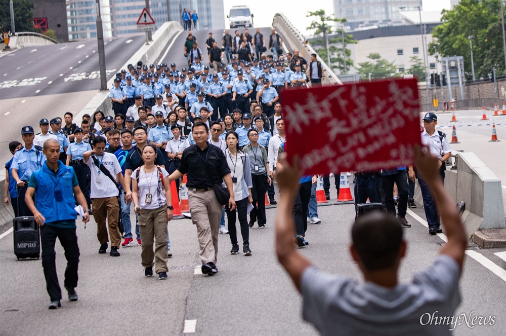  17일 오전 범죄인 인도법(일명 송환법) 폐지를 촉구하는 ‘검은 행진’에 참가한 홍콩 시민들에게 경찰들이 도로점거 철수를 요구하며 다가오자 한 시민이 손 피켓을 들고 마주하고 있다. 