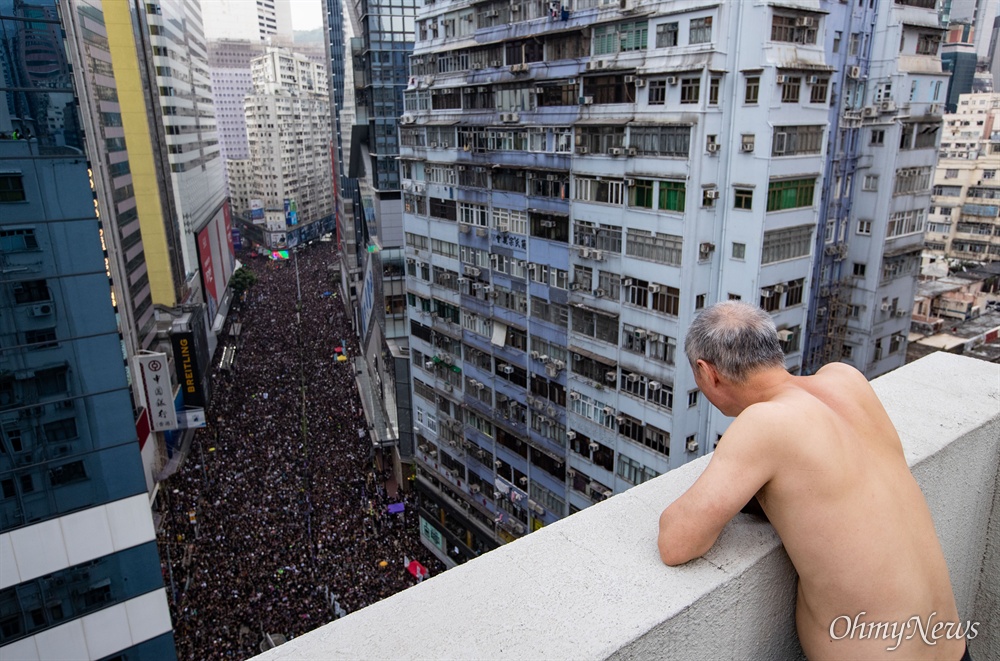  16일 오후 범죄인 인도법(일명 송환법) 폐지를 촉구하는 ‘검은 행진’ 참가자들이 홍콩 중앙정부청사를 향해 행진하는 모습을 목씨가 아파트 옥상에서 구경하고 있다.