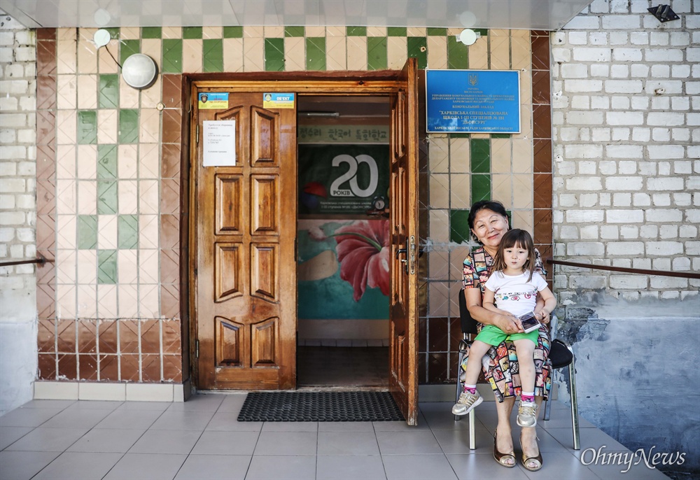  정수리 학교의 김 루드밀라 교장선생님이 손녀딸 김 리아(3세)와 함께 학교 정문 앞에서 기념사진을 찍고 있다.