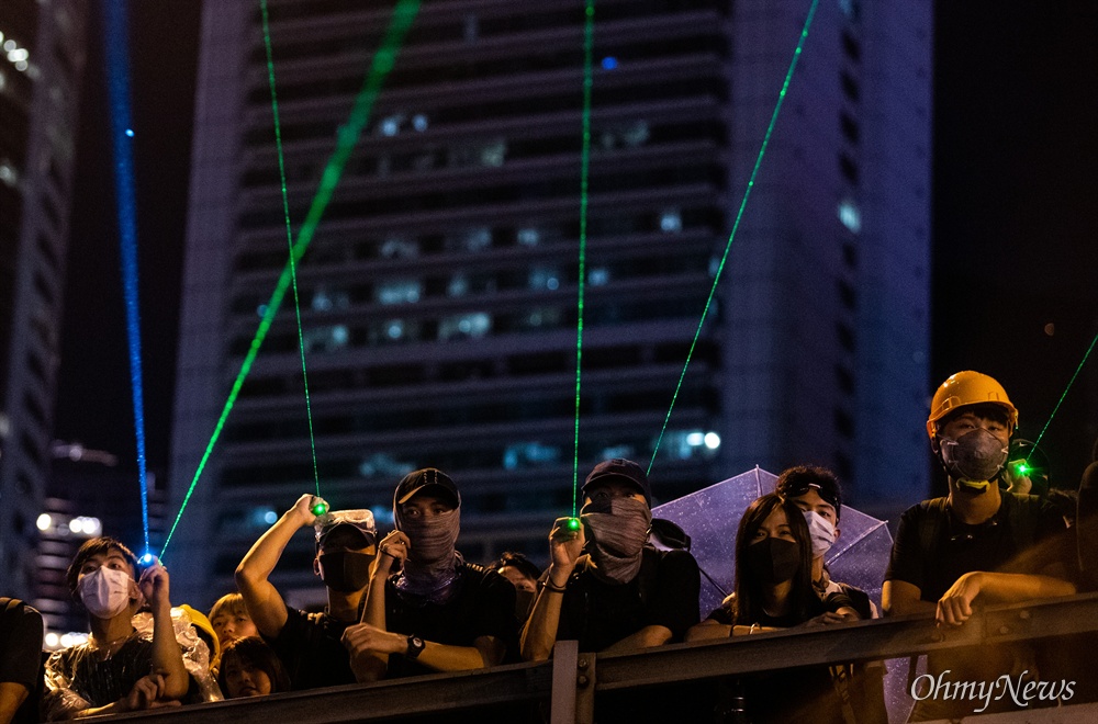 레이저 포인터 쏘는 홍콩시민들 18일 오후 홍콩 중앙정부청사 앞에서 송환법 반대 및 강경진압 규탄 행진을 마친 시위 참가자들이 정부청사를 향해 레이저 포인터를 쏘고 있다. 
