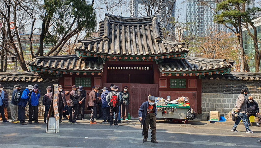  25일 서울 탑골공원 돌담길의 모습. 어르신들이 줄을 서서 무료급식을 기다리고 있다. 탑골공원은 2월 20일부터 문을 닫았다.