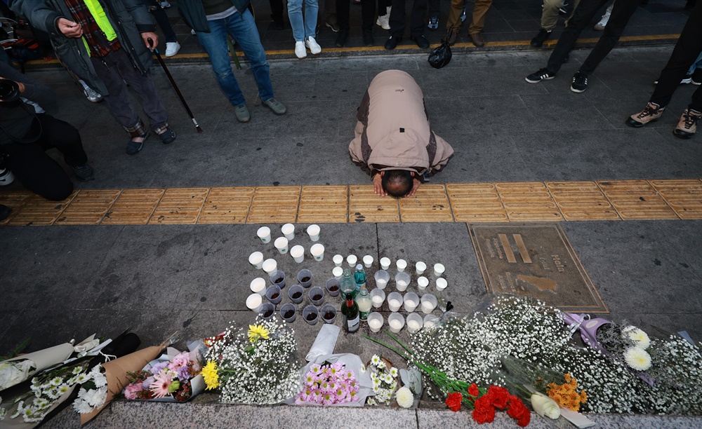  30일 오후 서울 용산구 지하철 6호선 이태원역 1번 출구 앞에 마련된 '핼러윈 인파' 압사 사고 희생자 추모 공간에서 한 시민이 술을 올린 뒤 절을 하고 있다.