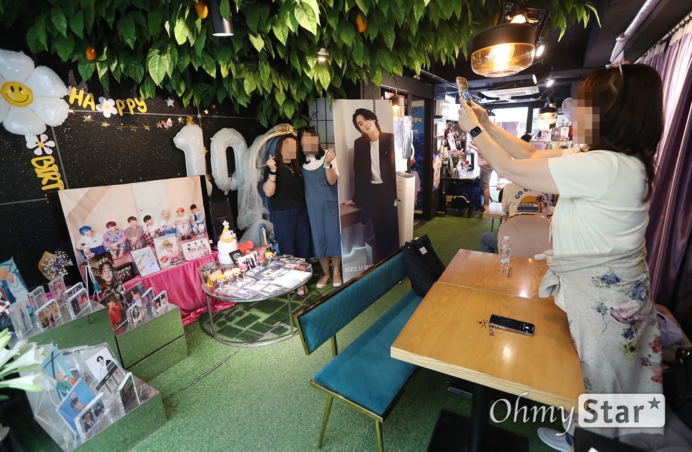 방탄소년단 10주년 방탄소년단 10주년을 맞아 14일 오후 서울 용산구 하이브 사옥 인근 카페에서 아미들이 방탄소년단의 사진과 구즈를 배경으로 기념촬영을 하고 있다.
