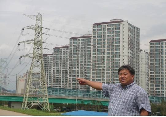 양산시의회 박말태 시의원이 신도시 송천철탑을 가리키고있다.