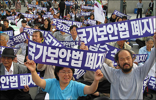 국가보안법 위반 혐의로 처벌을 받고 풀려난 사진작가 이시우씨가 지난 9월 아내 김은옥씨와 함께 서울역 광장에서 벌어진 국가보안법 폐지 집회에서 '국가보안법 폐지' 팻말을 들고 동참하고 있다.