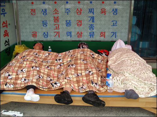 경북 고령군의 한 식당 처마 밑에서 이재오 의원이 낮잠을 자고 있다. 맨 오른쪽 수건으로 얼굴을 가린 사람이 이재오 의원. 맨 왼쪽은 윤건영 의원. 이재오 의원의 발가락 양말이 눈에 띈다. 