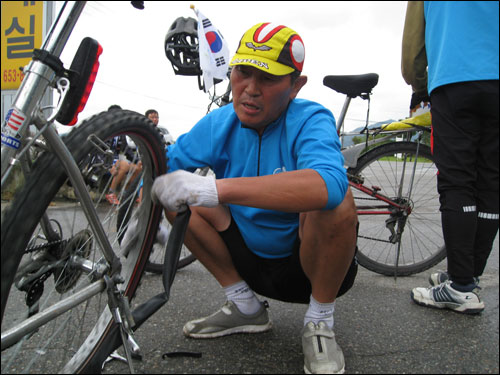 이재오 의원 탐방팀에서 오마이뉴스-환경연합팀의 펑크난 자전거를 수리해주고 있다.