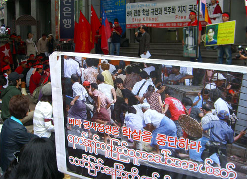버마 긴급행동 집회 참가자가 '버마 군사정권은 학살을 중단하라'는 피켓을 들었다.