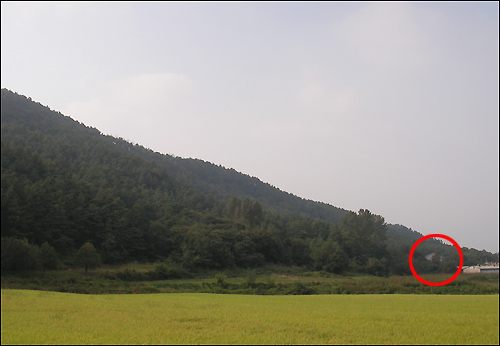 폐금광 갱도가 있는 광천읍 담산리 앞산 기슭(붉은 원). 오른쪽 끝 건물이 축사다.