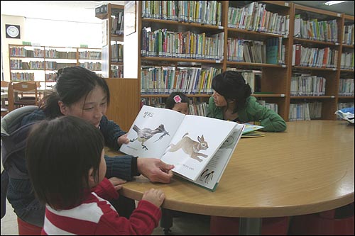 충남학생회관 정보관에서 엄마아 아이가 함께 그림책을 보고 있다.