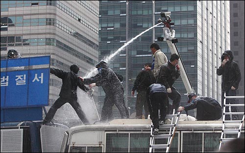 11일 오후 서울시청 부근에서 열린 '한미FTA 저지, 비정규직 철폐, 반전평화를 위한 2007범국민행동'에 참석했던 노동자들이 경찰버스에 올라가자 경찰이 물대포를 쏘며 제지하고 있다.