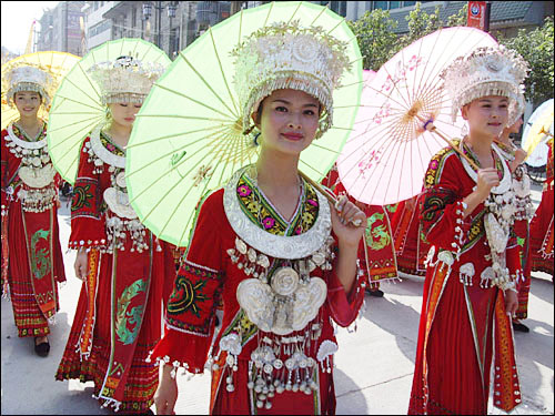 붉은 묘족 여성 혼례복을 입고 양산을 든 채 축제 퍼레이드를 벌이는 젊은 묘족 여성들.