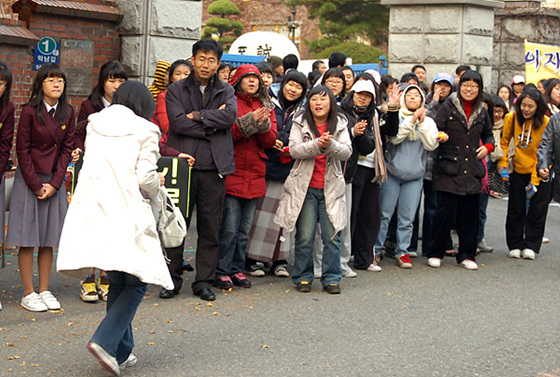   2008 수능 시험장인 인천 연수여고 교문 앞에  시간이 임박해서 도착한 수험생이 뛰어들어가자 후배들이 박수를 치며 용기를 주고 있다.