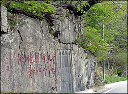 옛길 표지석 위 도로가의 암석에 준공 도로개설과정을 기록해 놓았다.