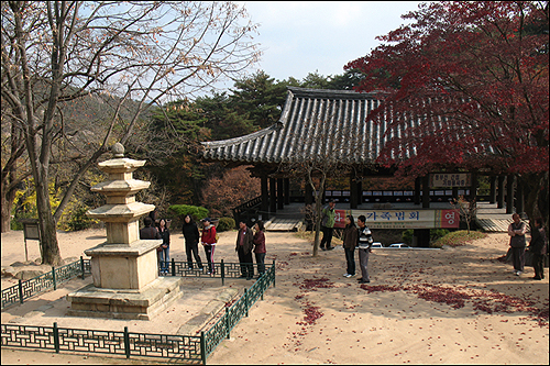  3층석탑(보물  제533호)과 절 입구를 지키는 만세루. 답사객들이 문화관광해설사의 해설을 듣고 있다. 