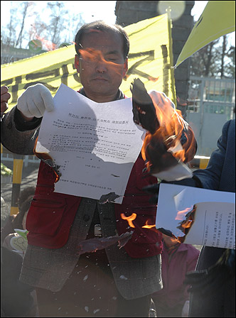 주병준 무건리훈련장확장저지를 위한 주민대책위원장이 국방부 정문 앞에서 국방부가 보낸 '주민이주신청서'를 불태우고 있다.