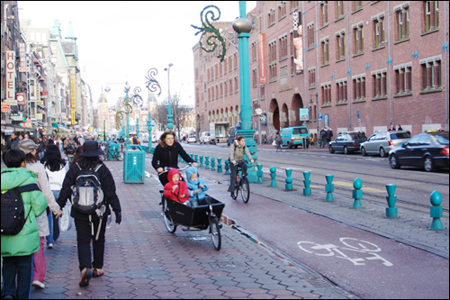 네덜란드 암스테르담 중앙역 앞. 차도·인도와 구분돼 있는 자전거전용도로가 인상적이다. 한 시민이 유모차가 연결된 자전거를 타고 지나고 있다. 네덜란드에서는 흔한 모습이다. 
