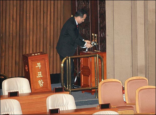 한나라당 의원들이 '이명박 특검'과 BBK수사검사 탄핵을 저지하기 위해 국회 본회의장을 점거한 가운데 14일 오전 김충환 의원이 본회의장 출입문을 노끈으로 묶고 있다.
