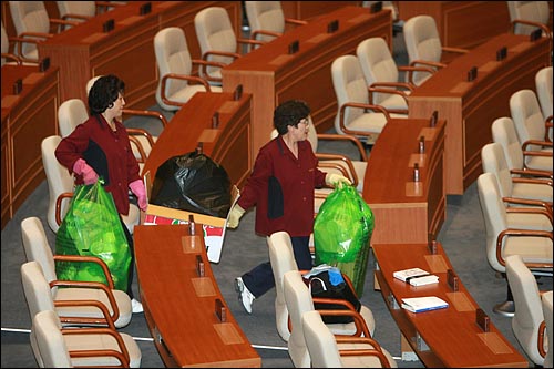  한나라당 의원들이 '이명박 특검'과 BBK수사검사 탄핵을 저지하기 위해 국회 본회의장을 점거한 가운데 14일 낮 농성중인 국회의원들이 먹은 도시락을 청소원들이 쓰레기봉투에 담아 치우고 있다.