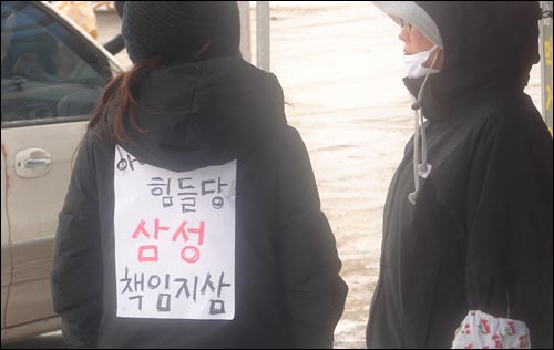 한 자원봉사자가 삼성의 성의있는 태도를 촉구하는 '아이고 힘들당 삼성 책임지삼'이라는 글을 등에 붙이고 있다.