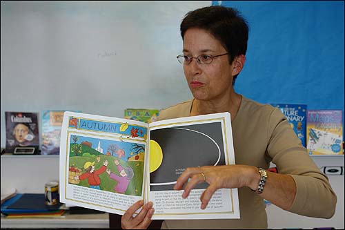 베이커 스쿨의 쉬마 컬스타인 교사가 글쓰기 수업에 활용하는 그림책 한 권을 들어 보이고 있다. 학생들에게 글감을 줄 때에 관련되는 그림책을 보여 주면서 학생들의 상상력을 자극하는 방식이다.