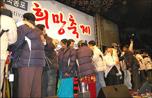 한희년 대표 목사들이 외국인노동자 및 중국동포들에게 방한복을 입혀주며 포옹하고 있다.