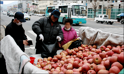 노부부가 사과값을 흥정하고 있다.
