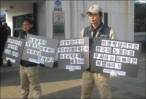  29일 오후 이명박 대통령 당선인이 인천 GM대우 부평공장을 방문하자, 비정규직 노동자들이 공장 정문 앞에서 비정규직 문제를 해결해달라는 내용의 피켓을 들고 있다.