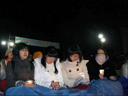 여고생 네 명이 나란히 앉아 촛불집회에 참가한 모습
