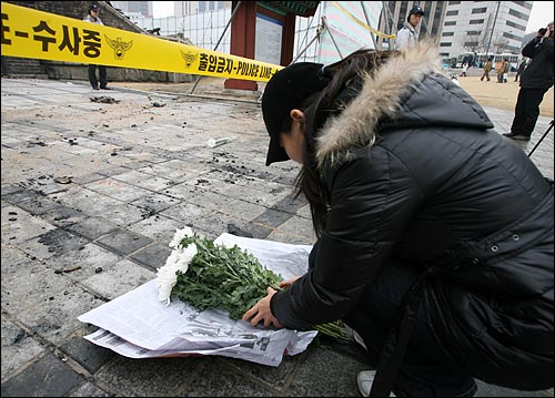 방화로 인해 전소된 서울 남대문로 숭례문앞에 11일 오전 한 시민이 국화꽃을 놓으며 흐느끼고 있다.