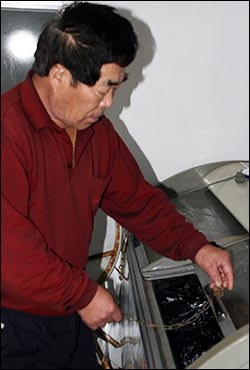 1호집의 옛주인. 밍크고래고기를 저장해둔 냉장고를 열어보인다.