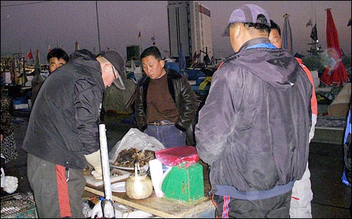 어시장이 파할 무렵 주변의 상인들이 모여 고래고기 안주에 소주와 막걸리를 나눠마신다.