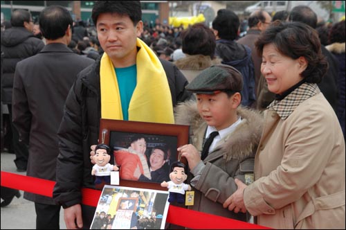 김진우군은 2002년 12월 노무현 전 대통령이 마산 어시장에서 선거 유세를 벌일 때 함께 찍었던 사진을 들고 나왔다.