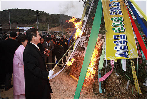 노무현 전 대통령이 부인 권양숙씨와 함께 25일 오후 고향인 김해 봉하마을에 도착해 지역주민, 전 각료, 노사모 회원들이 주최한 귀향 환영행사에서 짚불놀이에 불을 붙이고 있다.