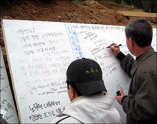 노무현 전 대통령 귀향 환영행사에 참가한 사람들이 '노무현에게 바라는 메시지'를 쓰고 있다.