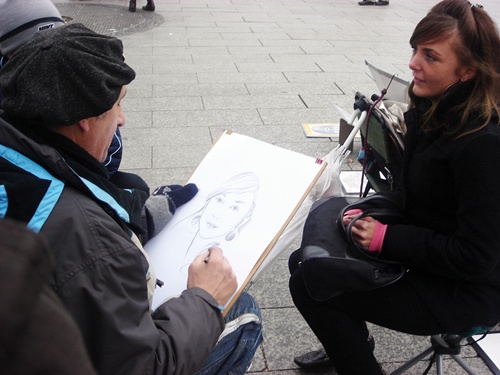 베를린 시내 길거리에서 한 화가가 앞에 앉은 여성의 얼굴을 그리고 있다.