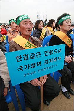  이날 행사에 참석한 장애인 관련 단체 회원들이 '한결같은 믿음으로 국가정책 지지하자'는 구호가 적힌 머리띠와 피켓을 들고 나왔다.