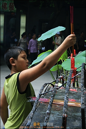 차오저우의 당나라 시대 사원 카이위엔쓰 천왕전 앞에서 향을 피우고 있는 아이