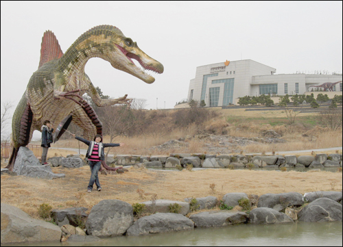  모형 공룡이 서 있는 박물관 야외공원. 멀리 보이는 건물이 실내 전시관이다.